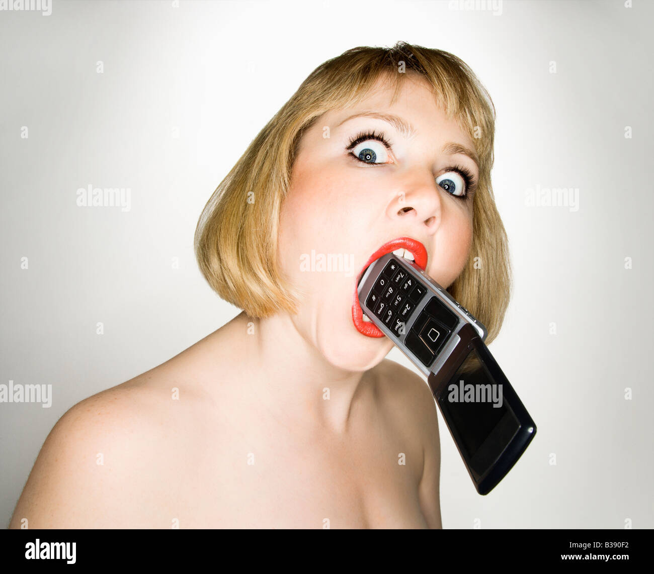 Portrait of young blonde caucasian woman who has a cellphone in her mouth Stock Photo