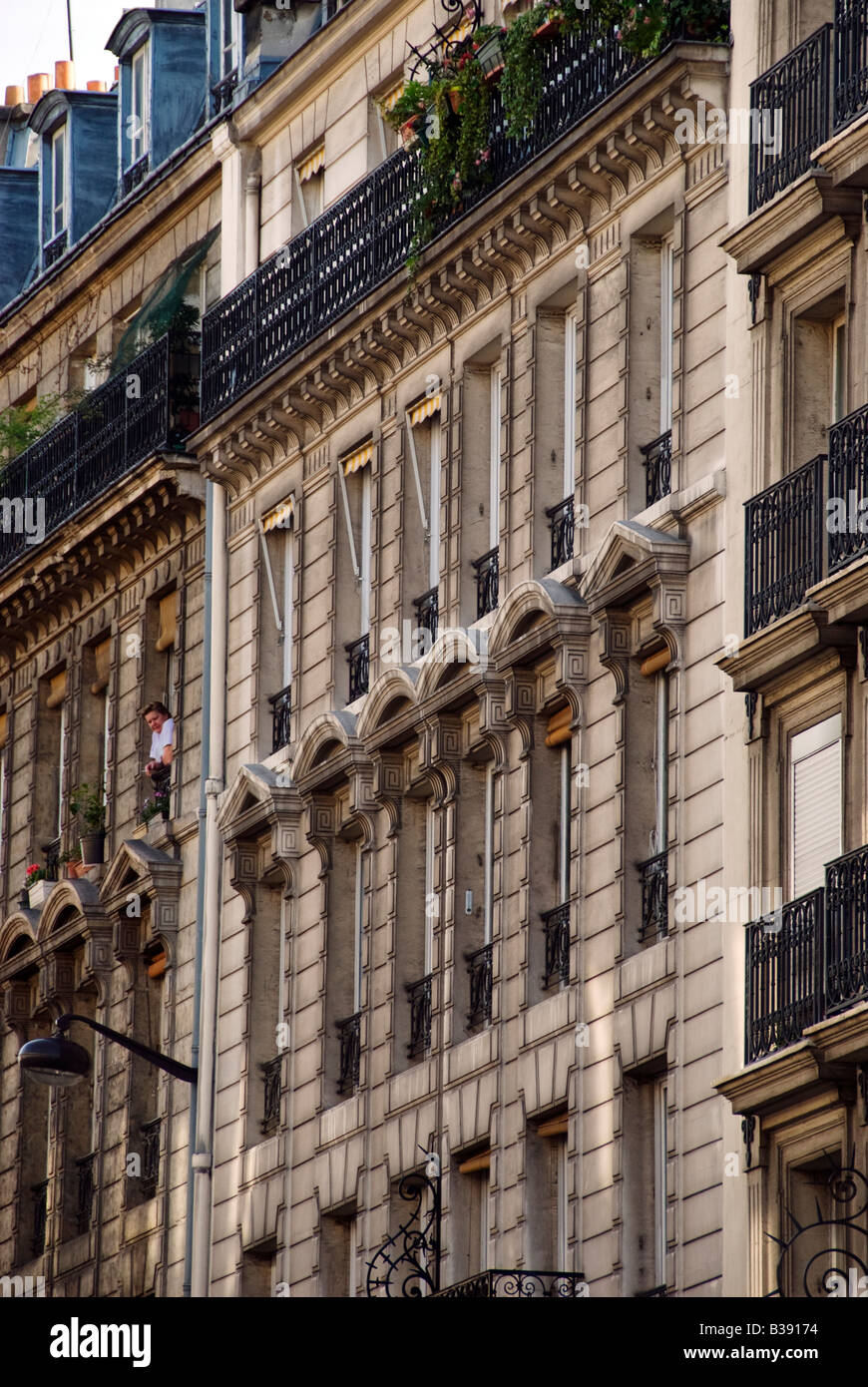 Paris facades of apartments with a woman smoking a cigarette in one of the apartments. Stock Photo