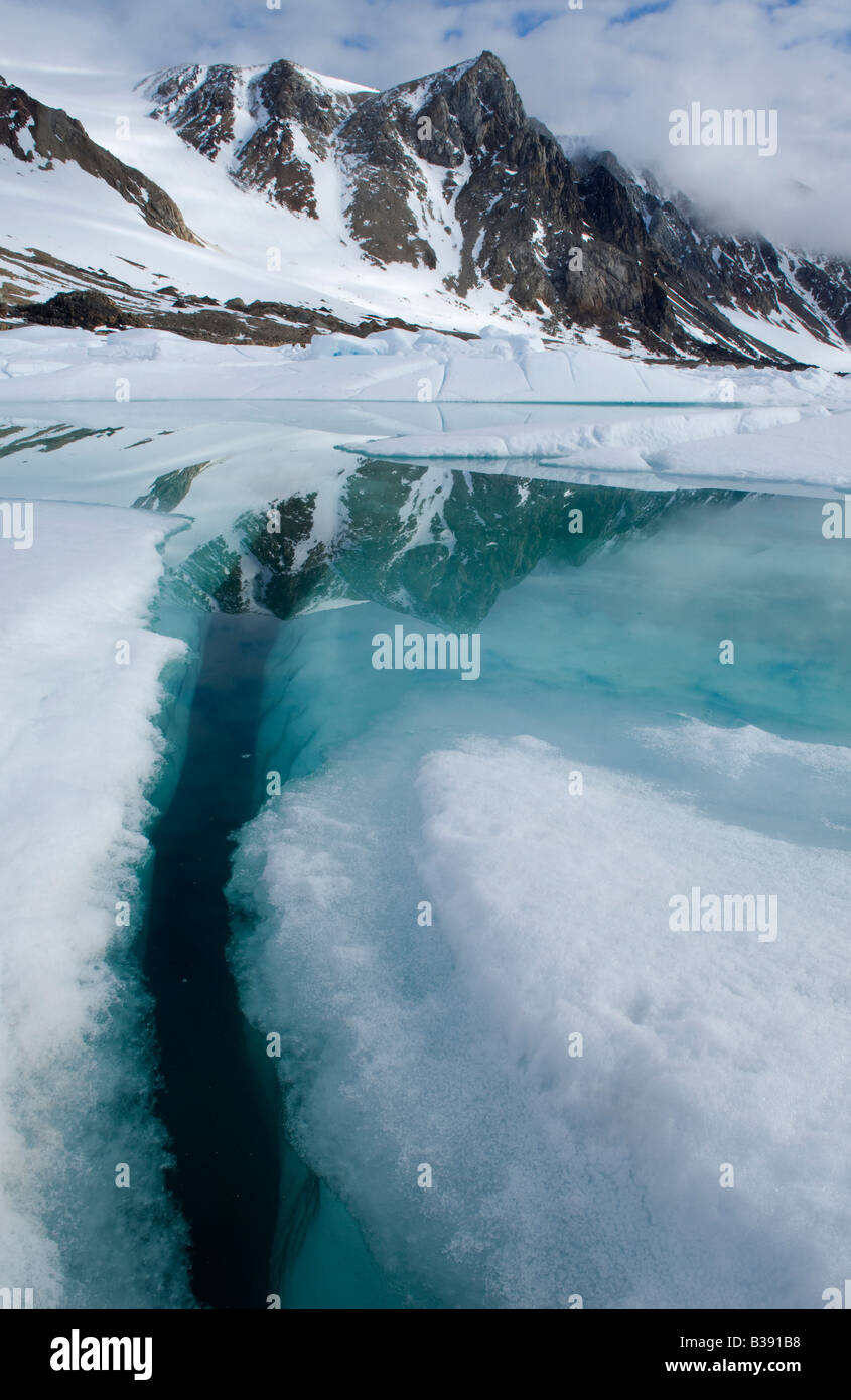 A small pool of Glacial Water reflecting the Mountains on Cobourg Island Stock Photo