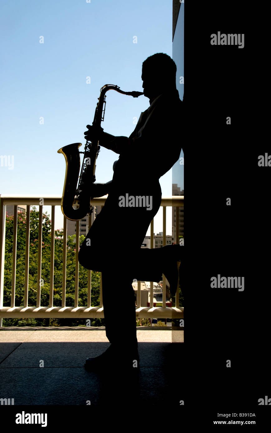 A saxophone player silhouetted against the bright daylight Stock Photo