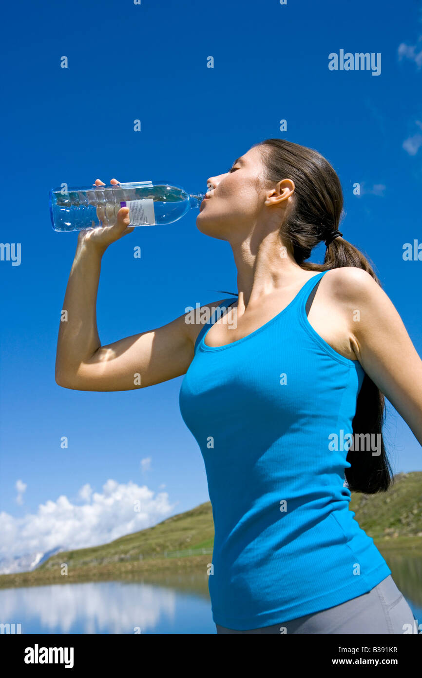 Junge Frau trinkt Wasser aus einer Glasflasche, young woman drinks water from glass a bottle Stock Photo
