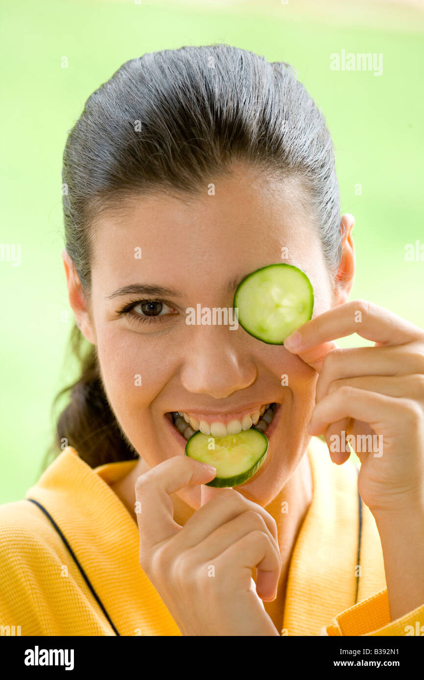Junge Frau mit einer Gurkenscheibe vor dem Auge, Young woman with a cucumber disk before the eye Stock Photo