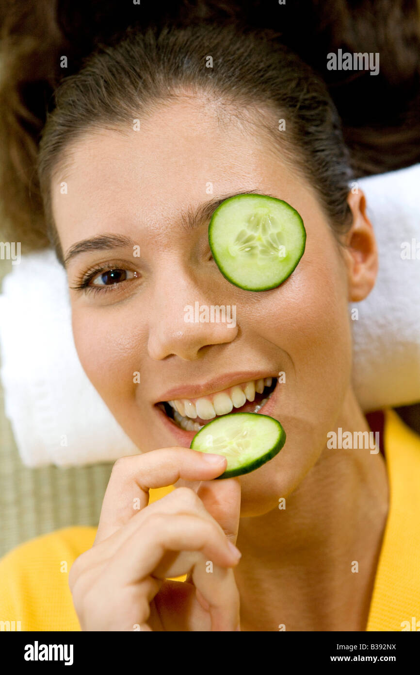 Junge Frau mit einer Gurkenscheibe vor dem Auge, Young woman with a cucumber disk before the eye Stock Photo