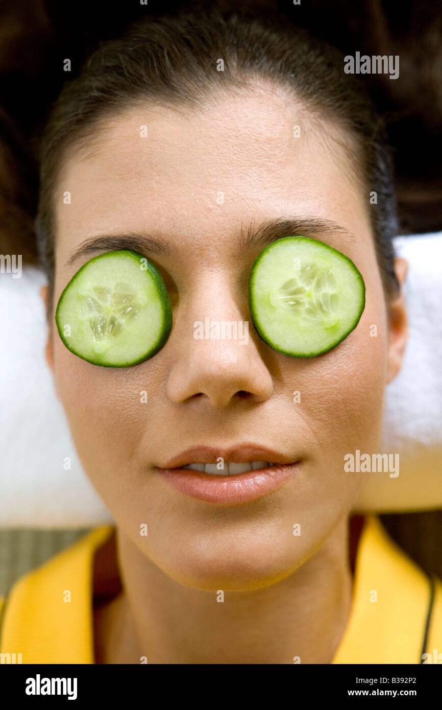 Junge Frau mit einer Gurkenscheibe vor dem Auge, Young woman with a cucumber disk before the eye Stock Photo