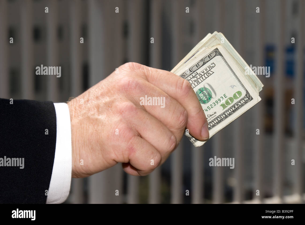 A businessman handing over a wad of cash Stock Photo