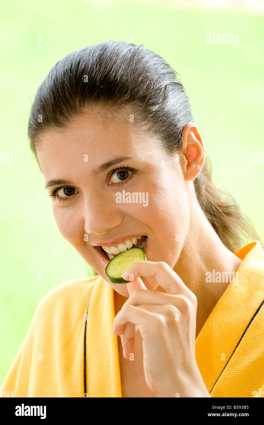 Junge Frau isst eine Gurkenscheibe, Portrait, young woman eating cucumber disk Stock Photo