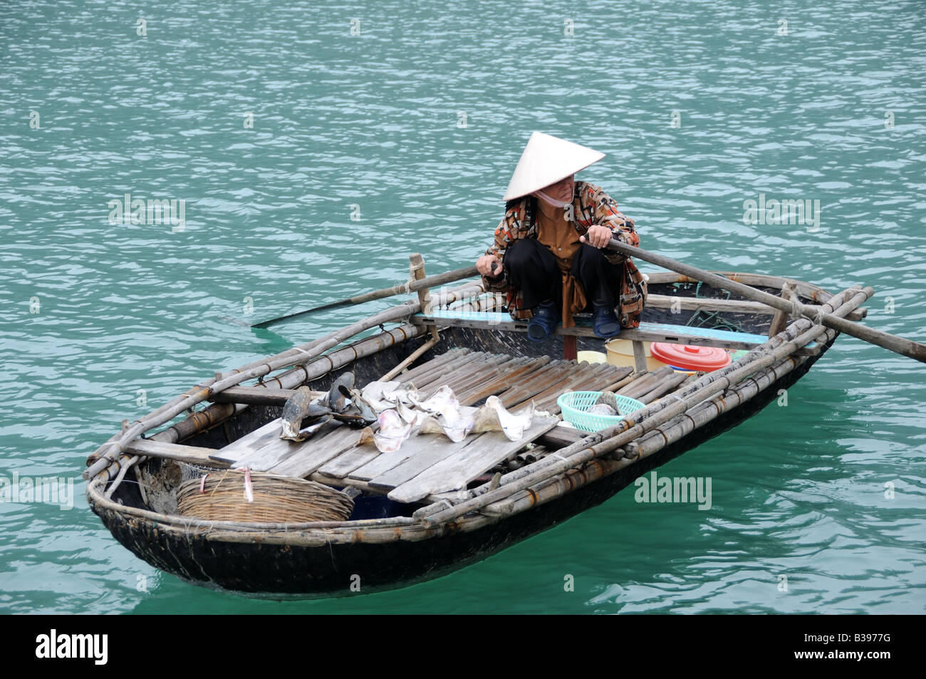 Agile Vietnamese woman selling shells from a small boat to make a living Halong Bay Vietnam Stock Photo