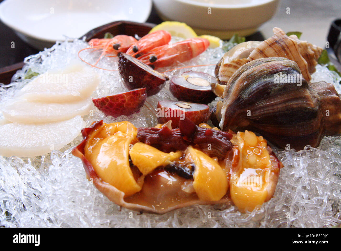 Korean seafood fresh half shell oysters prawns lychees white raddish and lemon on transparent noodles. Stock Photo