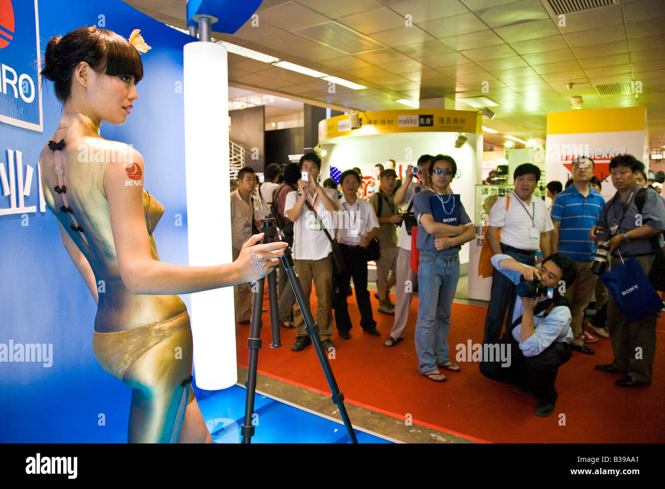 Chinese girl in bikini and gold paint on Benro tripod exhibition stand at photographic show in Beijing China July 2007 JMH3210 Stock Photo