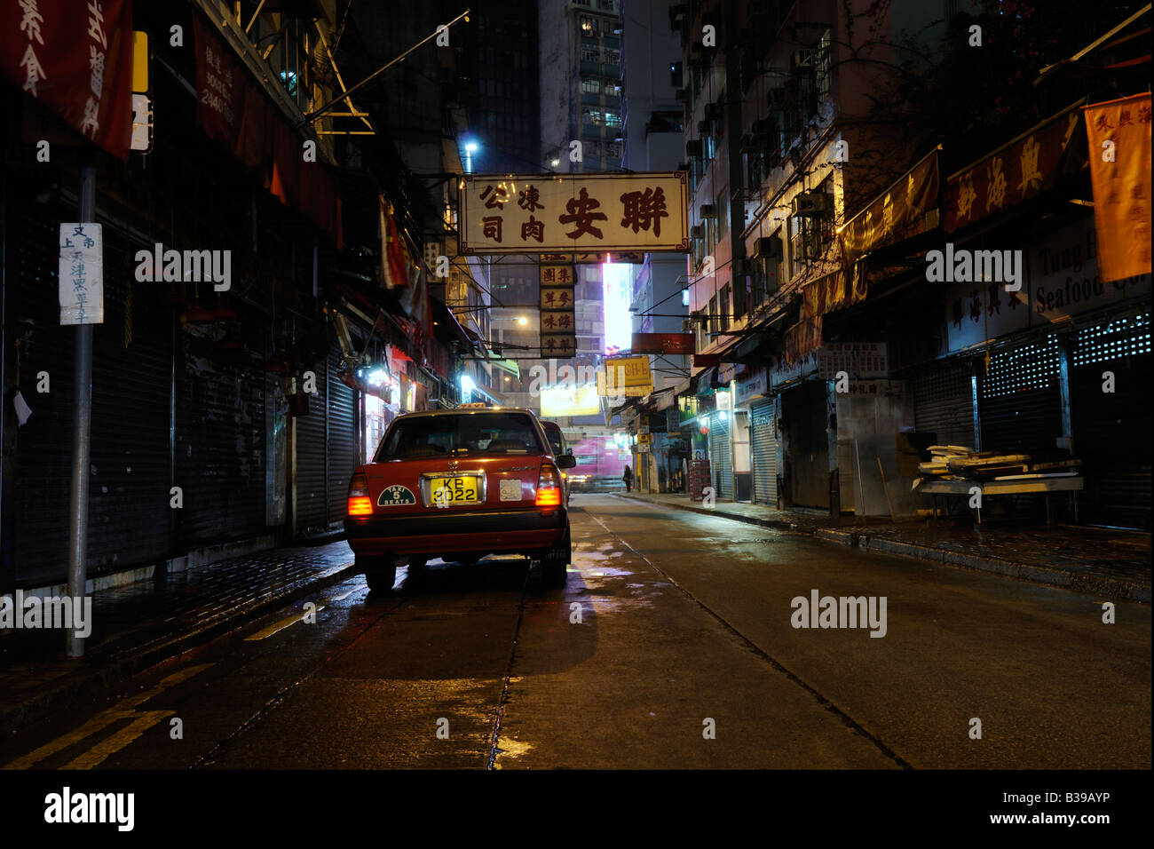 A Hong Kong taxi waiting while customer pays the fare at night in Wan Chai. Stock Photo