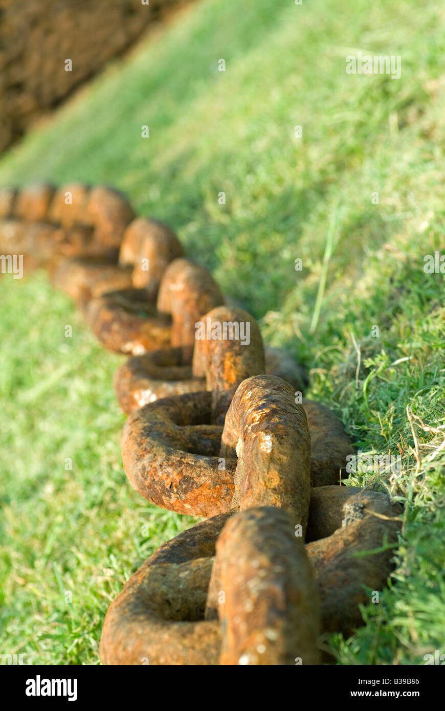long old rusty iron chain lying on grass Stock Photo