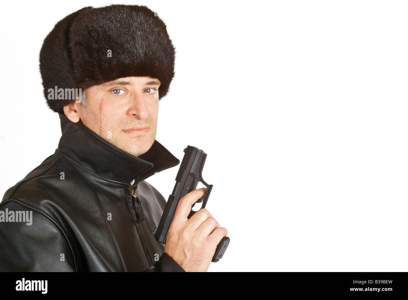 A Russian mafia figure with a large facial scar carrying a hand gun picture shot on a white background with copy space Stock Photo