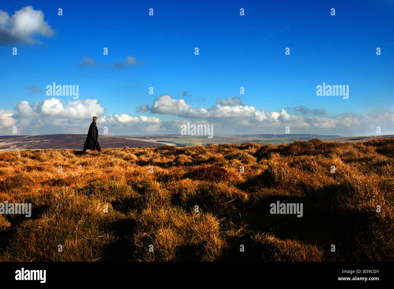 BOY IN LONG COAT WALKING ON MOORLAND Stock Photo