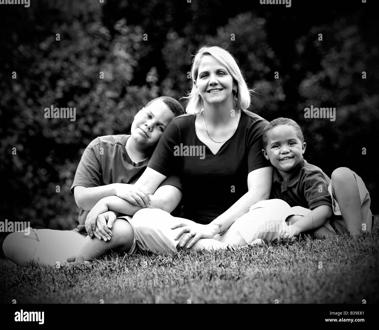 Pretty mom with her two sons outside on grass Stock Photo