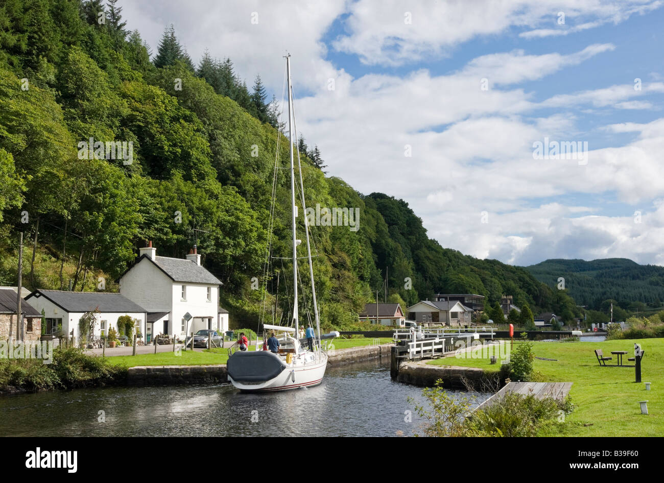 A Sailing vessel is approaching one of the locks on Crinan Canal at Cairnbaan in Argyll Scotland heading east towards Loch Fyne Stock Photo