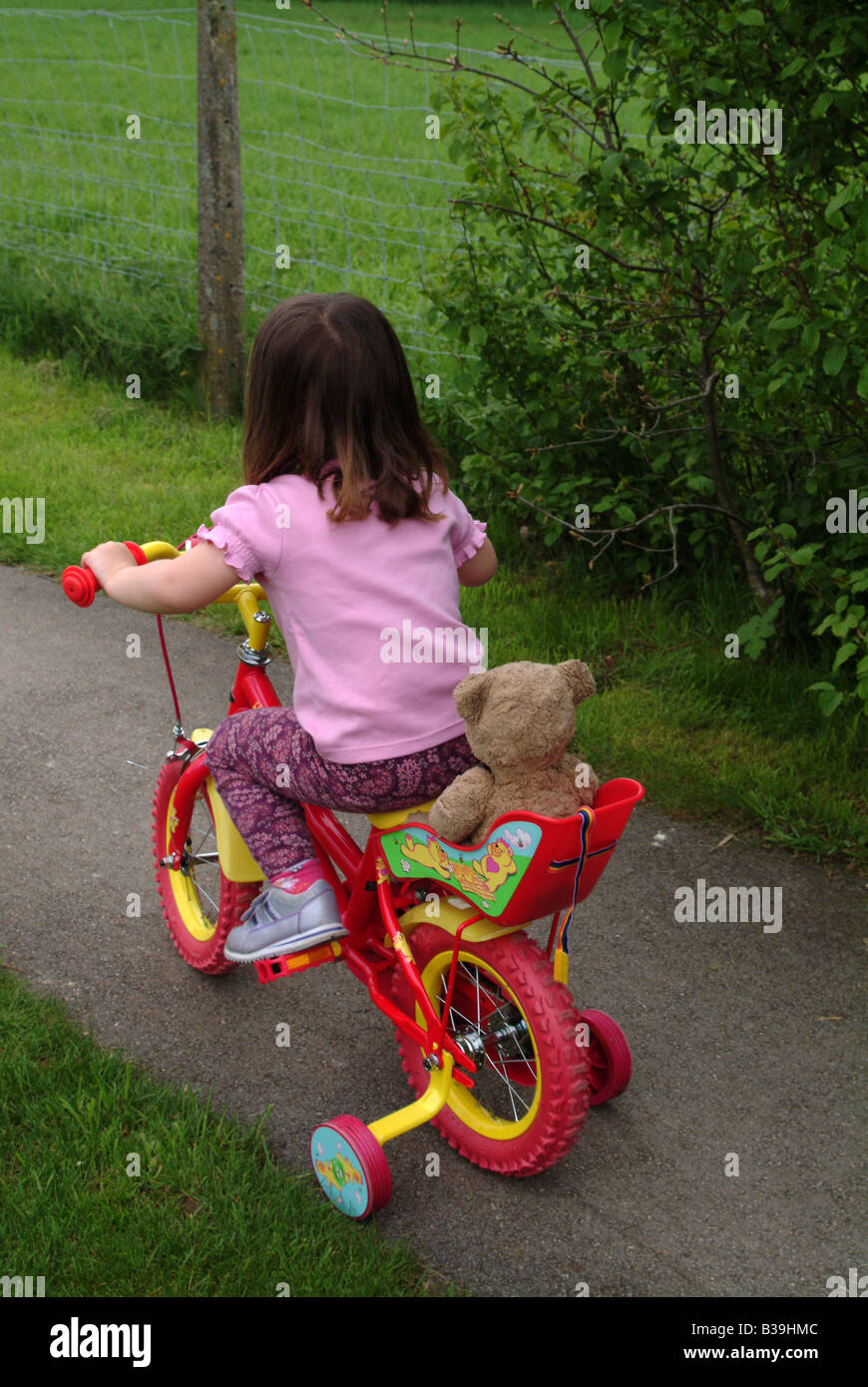 Rear view of a girl cycling with stabilisers Stock Photo