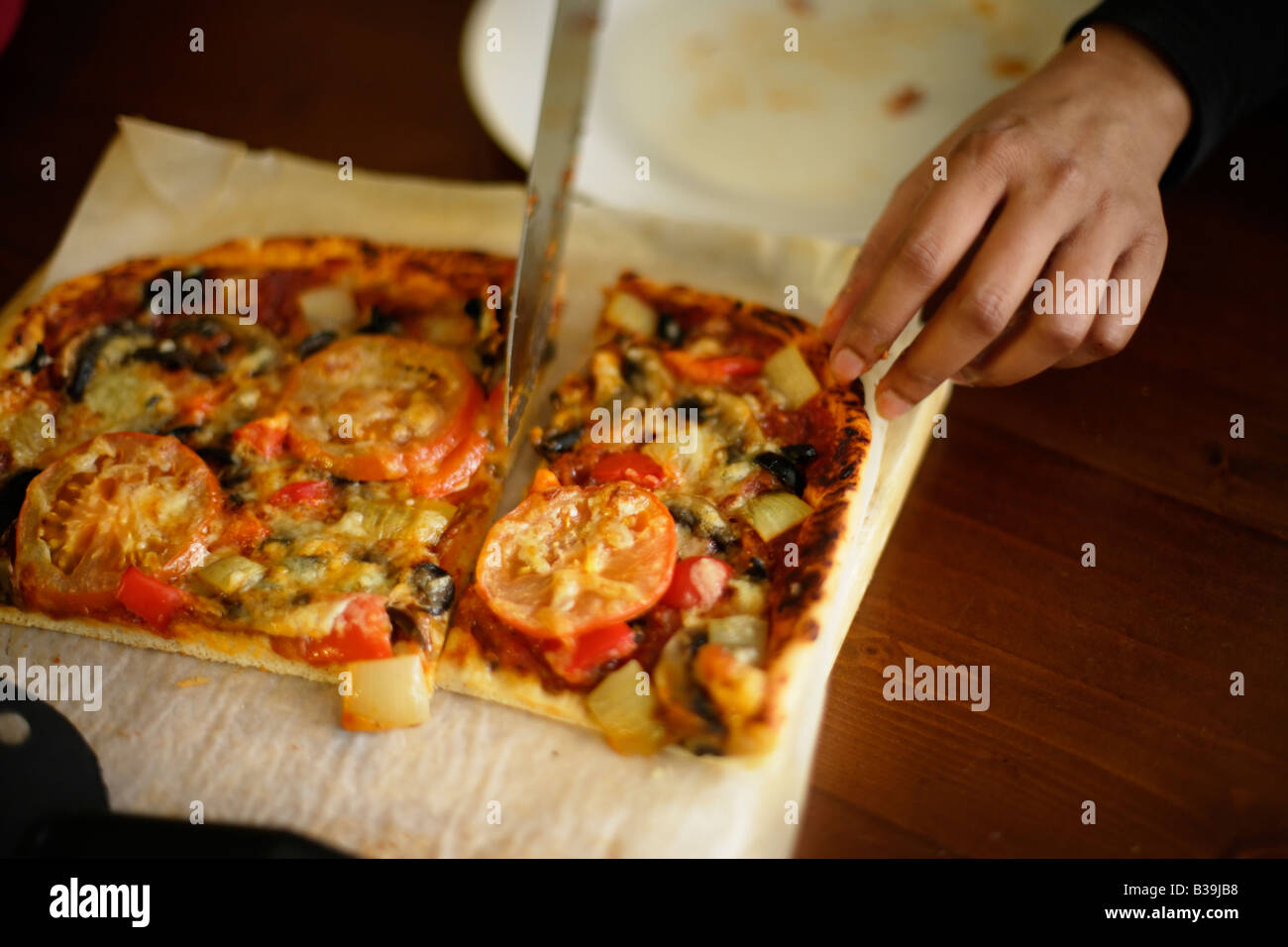 Homemade Pizza Indian woman cuts a slice Stock Photo