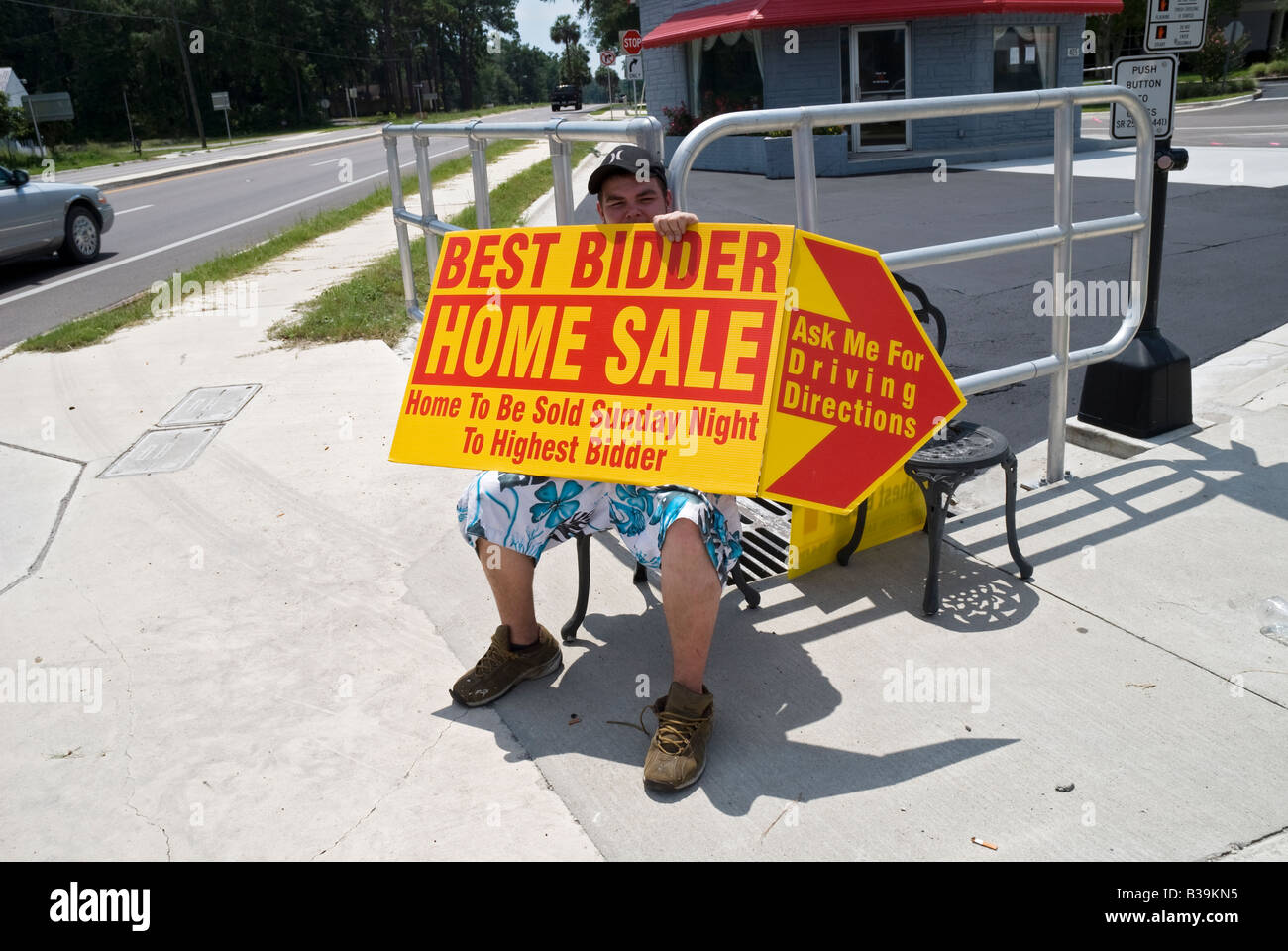 A man holds sign for home auction to the highest bidder on sidewalk of High Springs a small town in North Florida Stock Photo