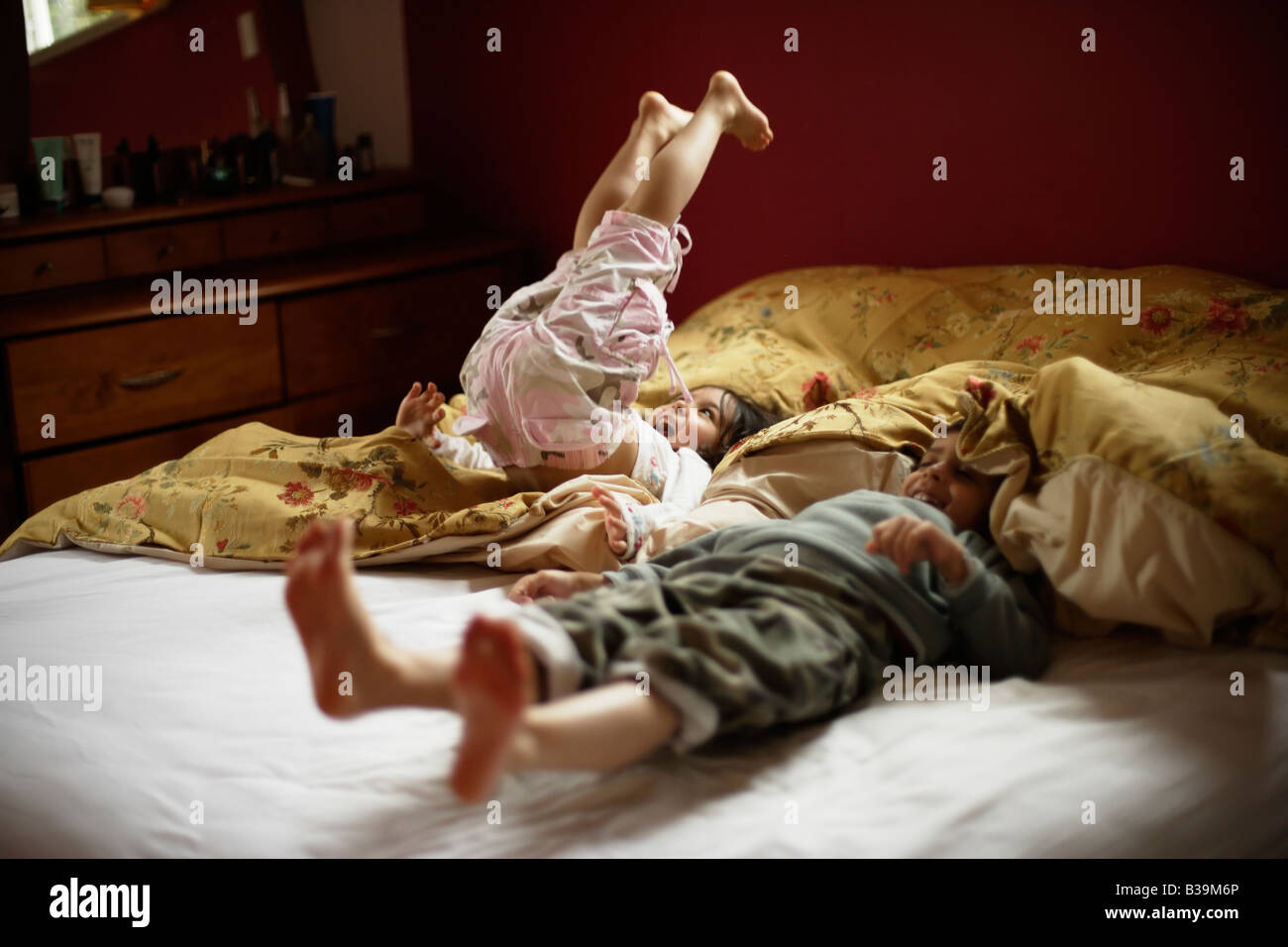 Brother and sister bounce on parent's bed Girl aged 5 and boy 6 Stock Photo