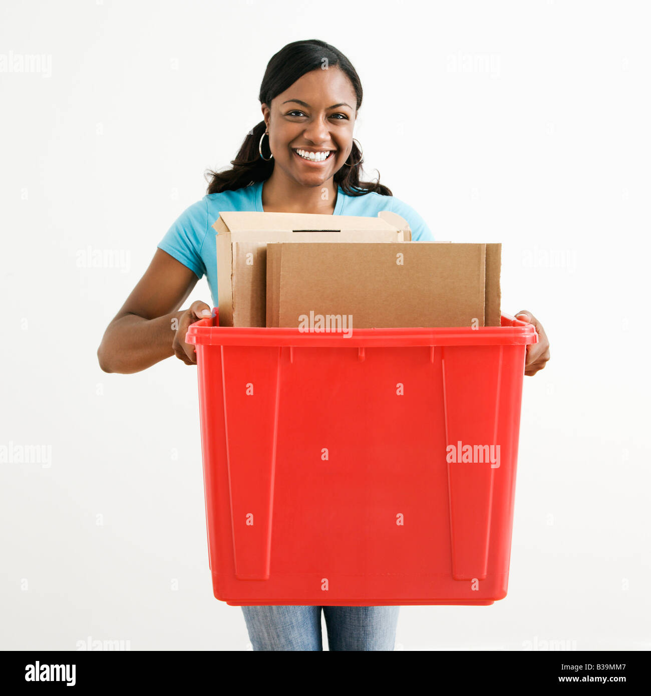 African American young adult female holding recycling bin with cardboard in it Stock Photo