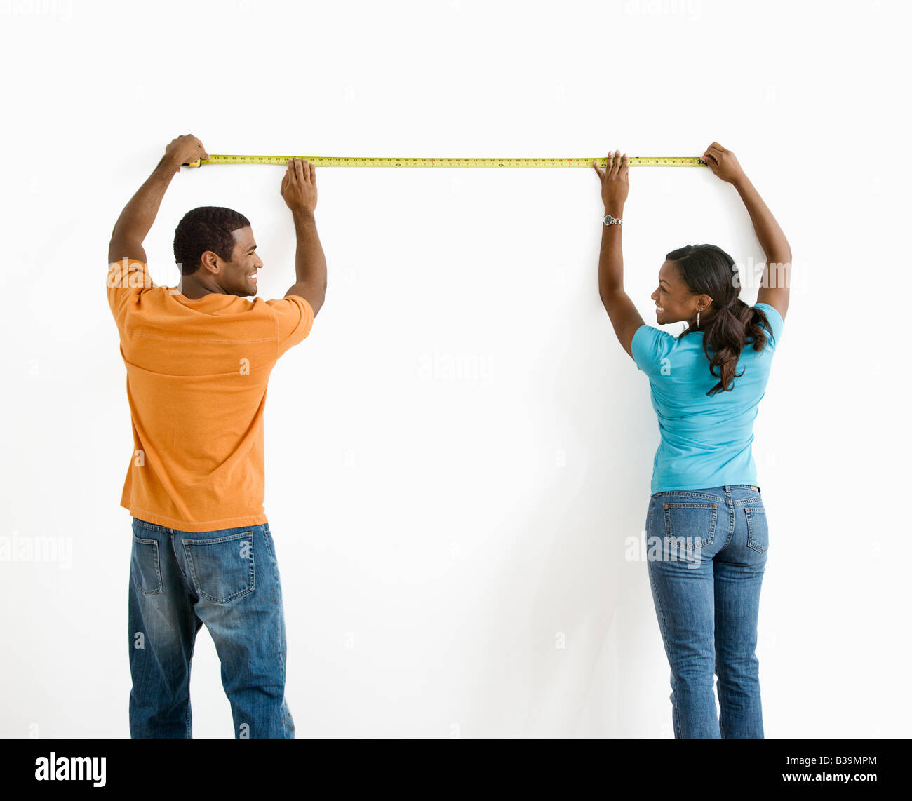 African American male and female measuring wall Stock Photo