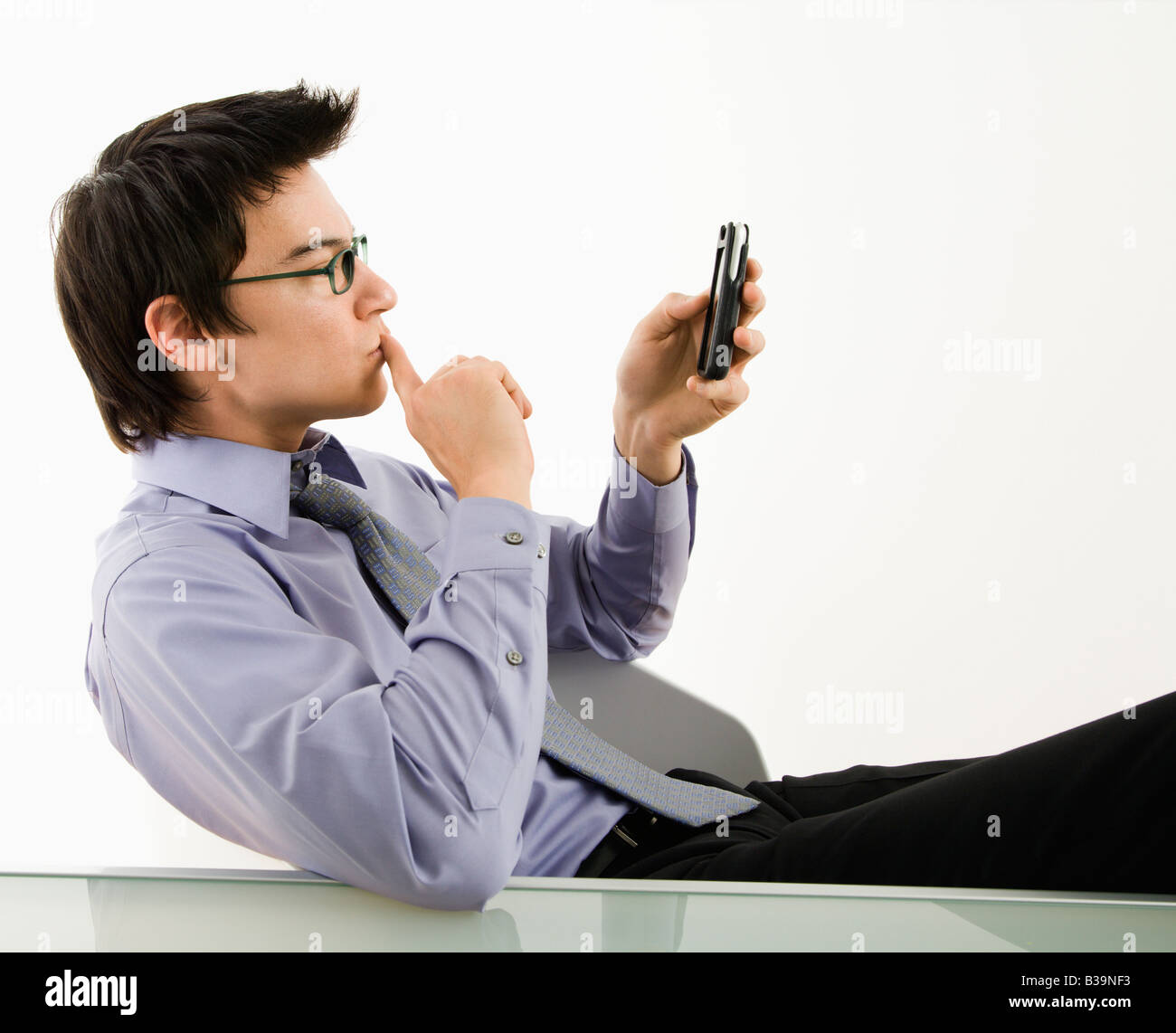 Asian businessman sitting at desk texting using his pda cellphone Stock Photo