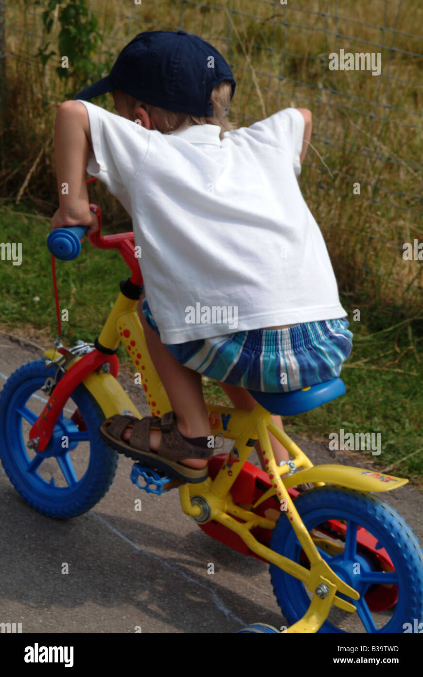 Rear view of a little boy on bike with stabilizers Stock Photo