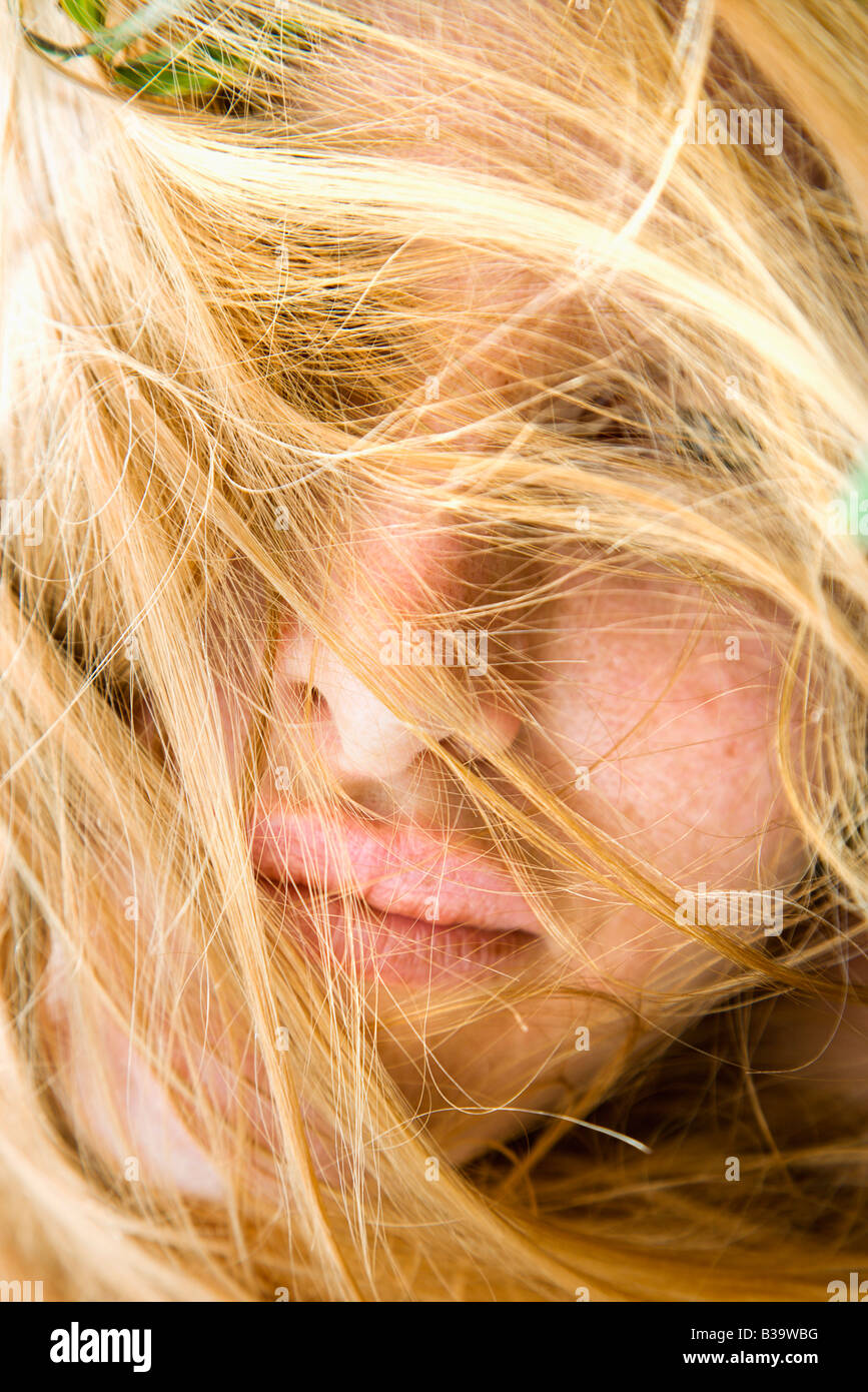 Close up portrait of redheaded woman with windblown hair covering face Stock Photo