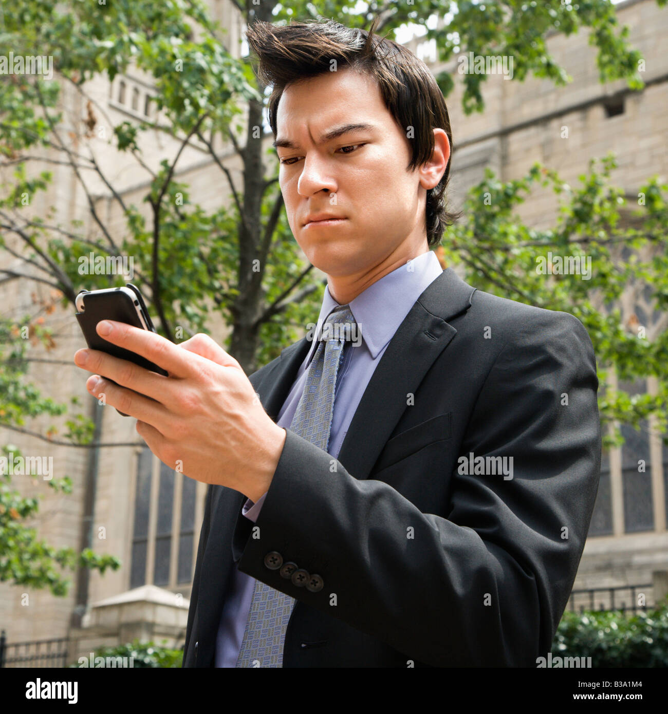 Asian business man standing looking at cell phone messages Stock Photo