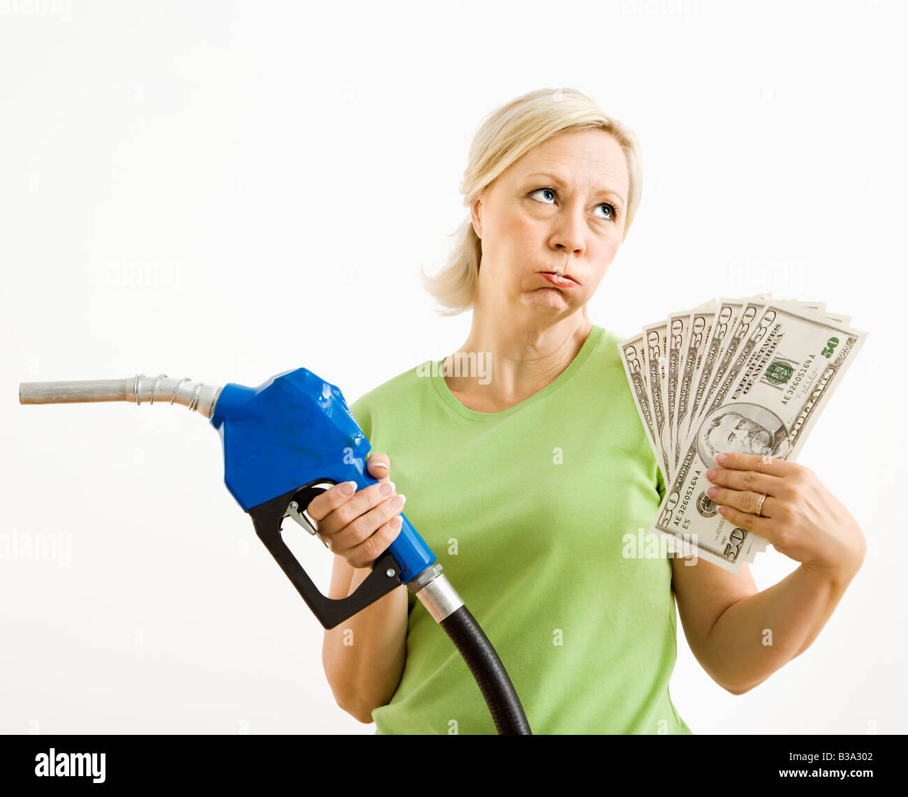 Portrait of distressed adult blonde woman holding gas nozzle and lots of money Stock Photo
