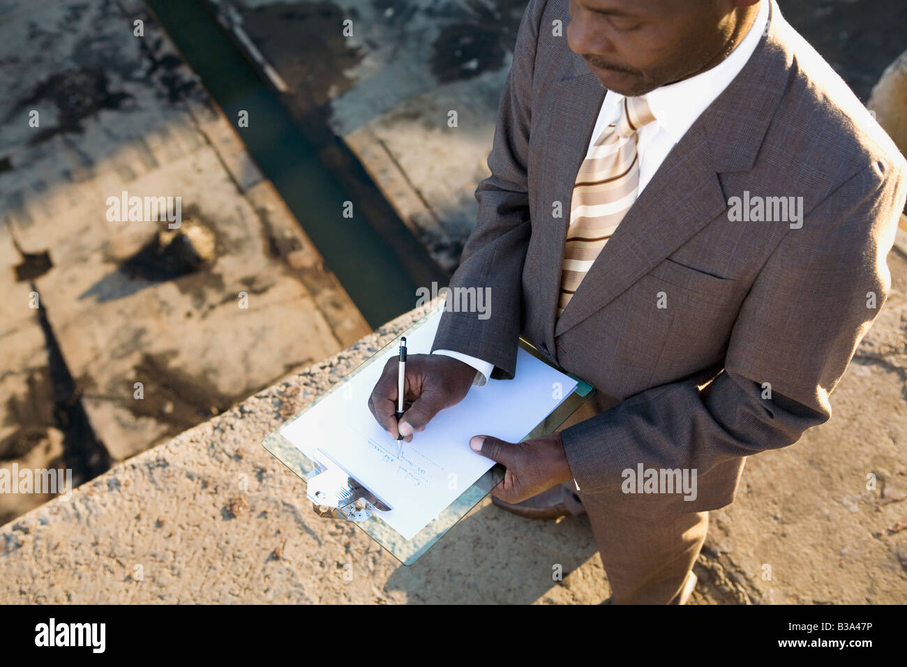 African American businessman writing on clipboard Stock Photo - Alamy