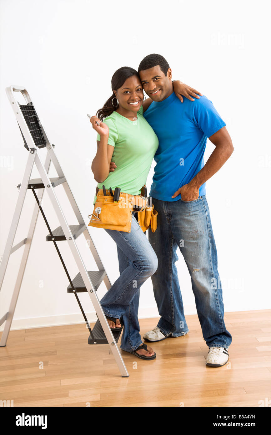Portrait of smiling African American male and female couple with home repair tools and ladder Stock Photo