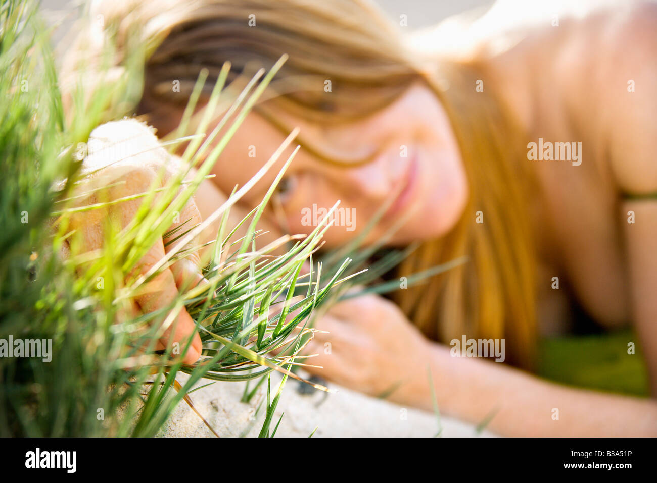 Selective focus portrait of young redheaded woman lying in grass looking at viewer Stock Photo