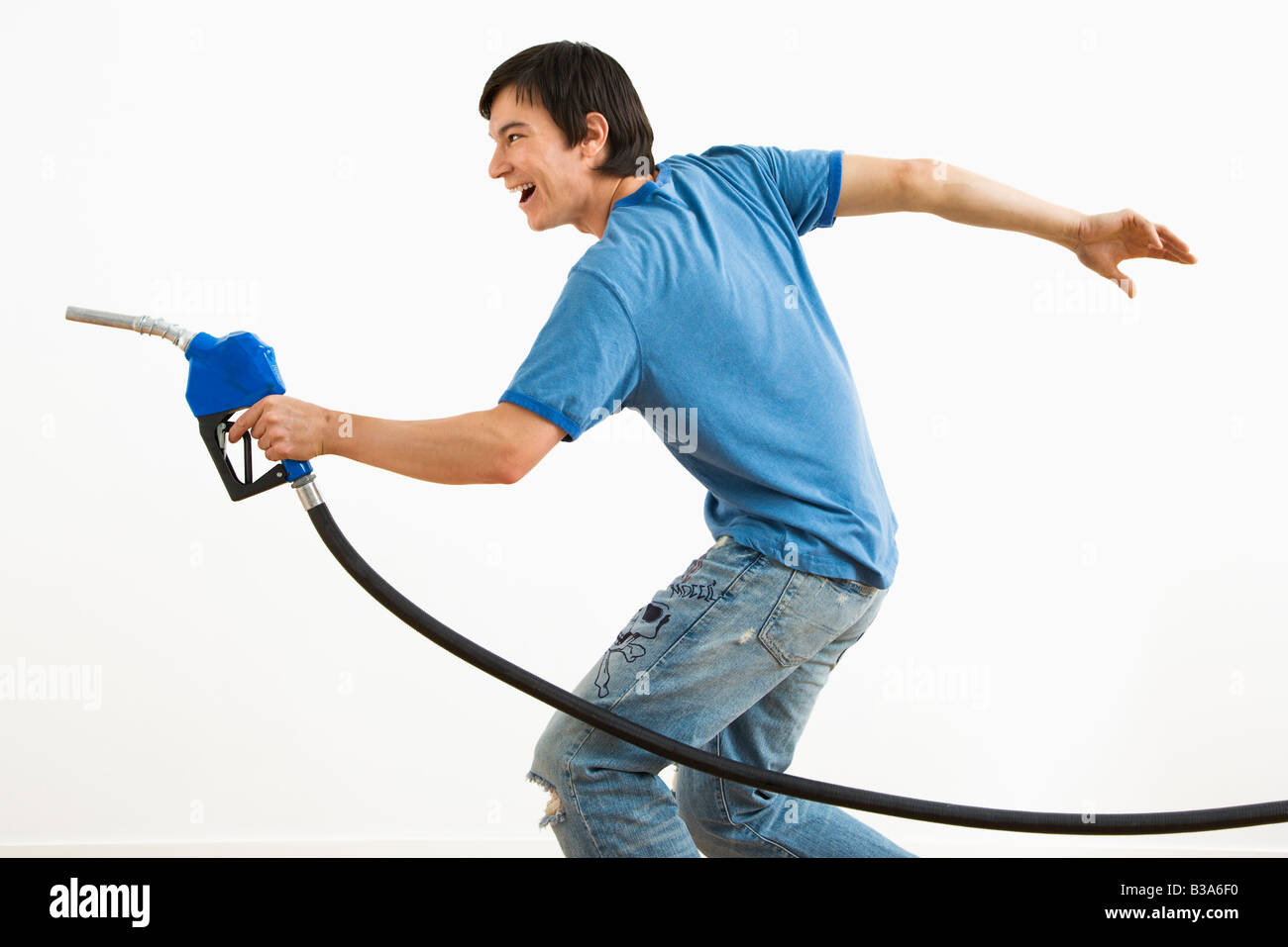 Asian young man aiming gasoline pump nozzle like a gun Stock Photo