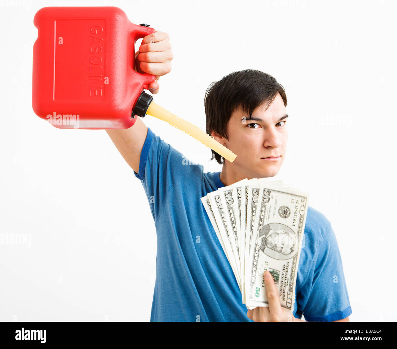 Asian young man holding gas can pouring gasoline onto money Stock Photo