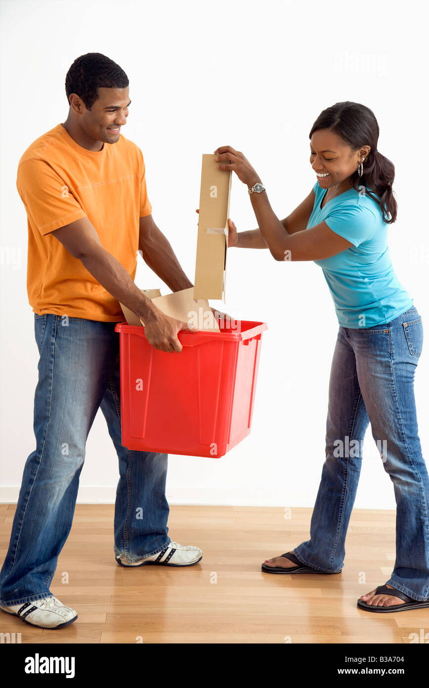 African American male holding recycling bin while pretty female puts