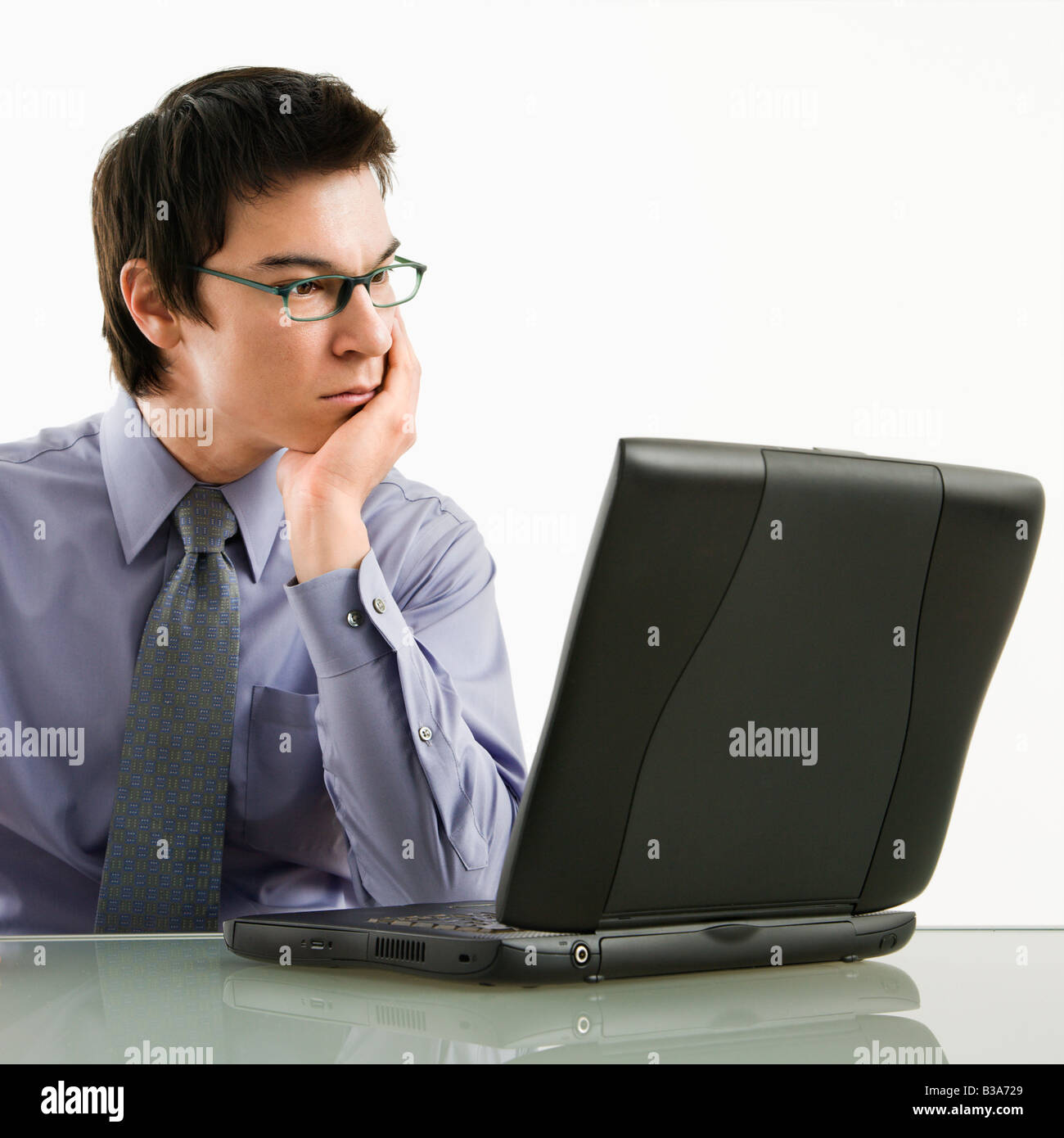 Asian businessman sitting at desk working on laptop computer Stock Photo