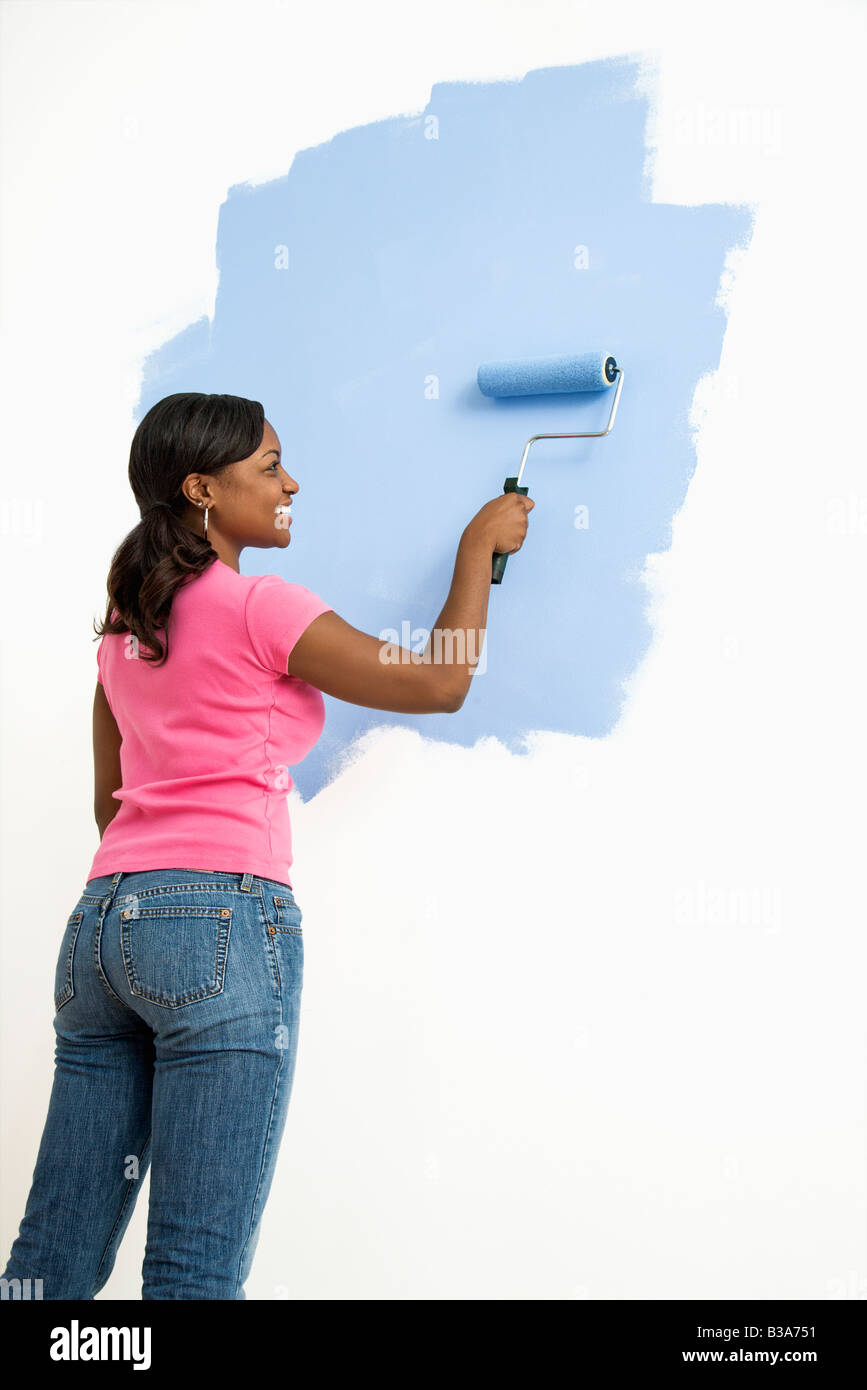 African American woman painting wall blue Stock Photo