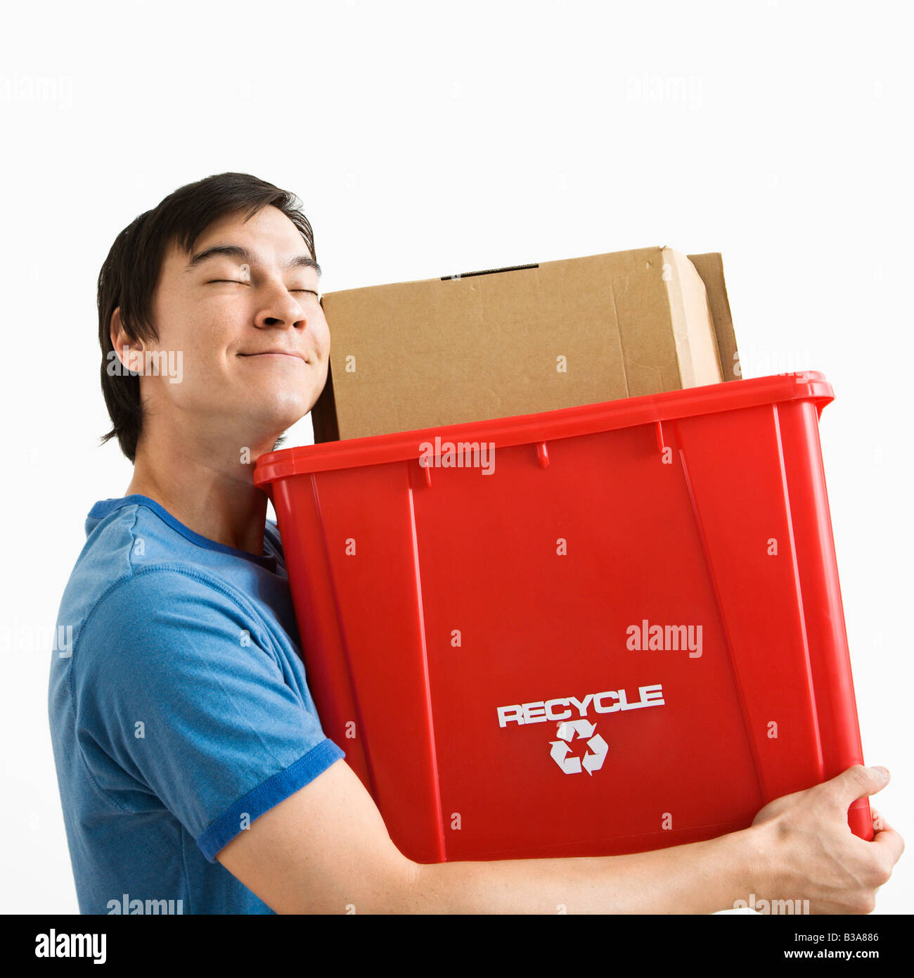 Portrait of smiling Asian young man holding recycling bin Stock Photo