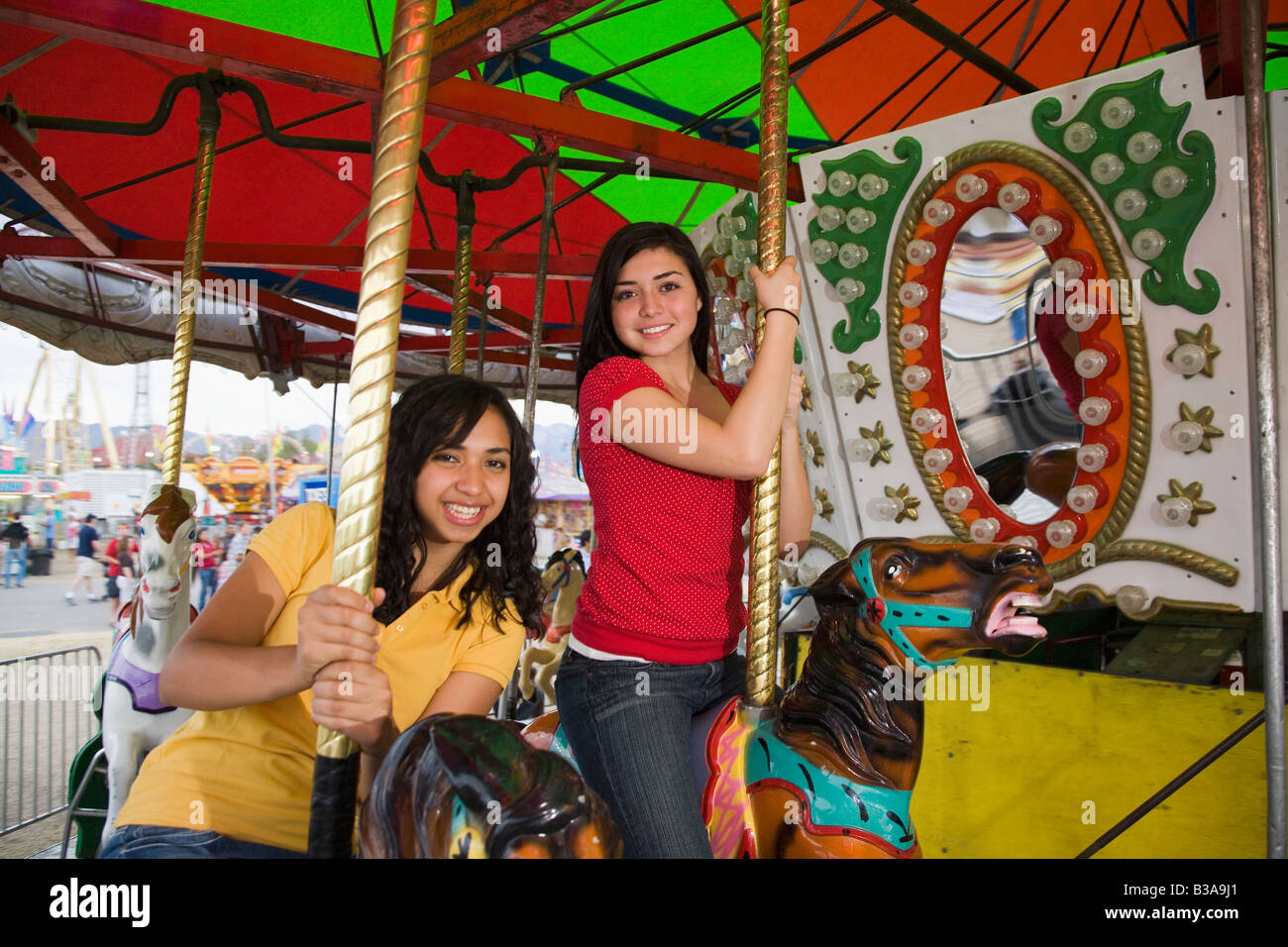 Mixed Race teenaged girls on carousel horse Stock Photo Alamy