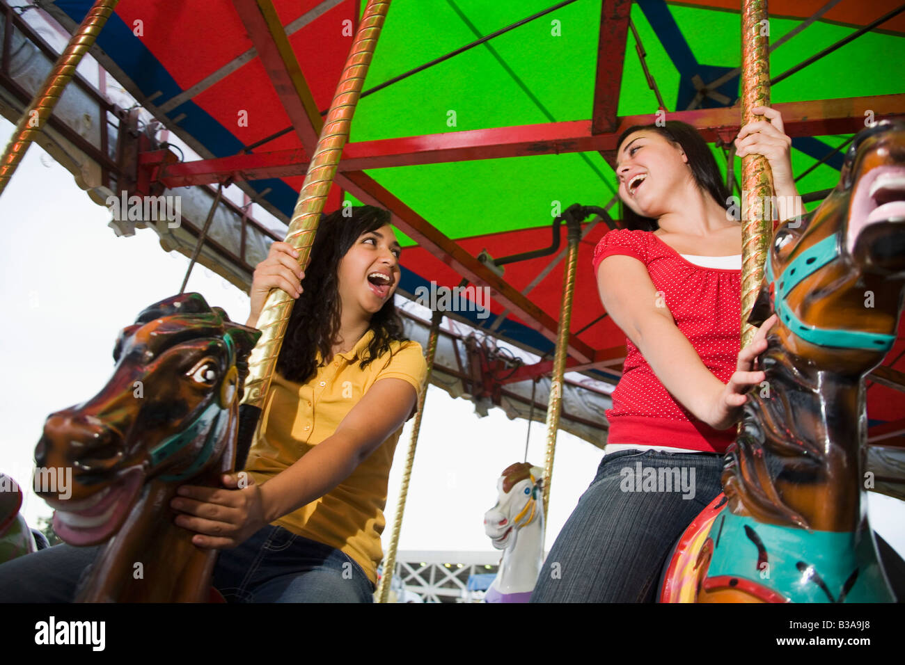 Mixed Race teenaged girls on carousel horse Stock Photo Alamy