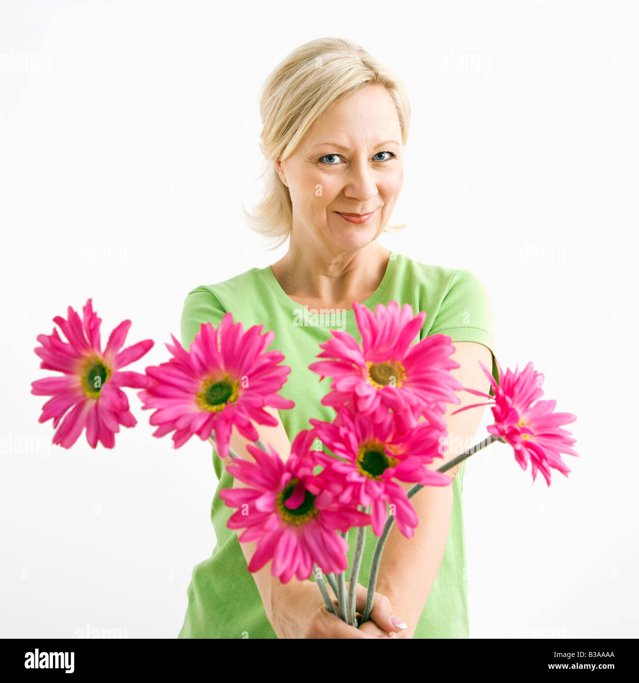 Portrait of smiling adult blonde woman giving bouquet of pink flowers to viewer Stock Photo