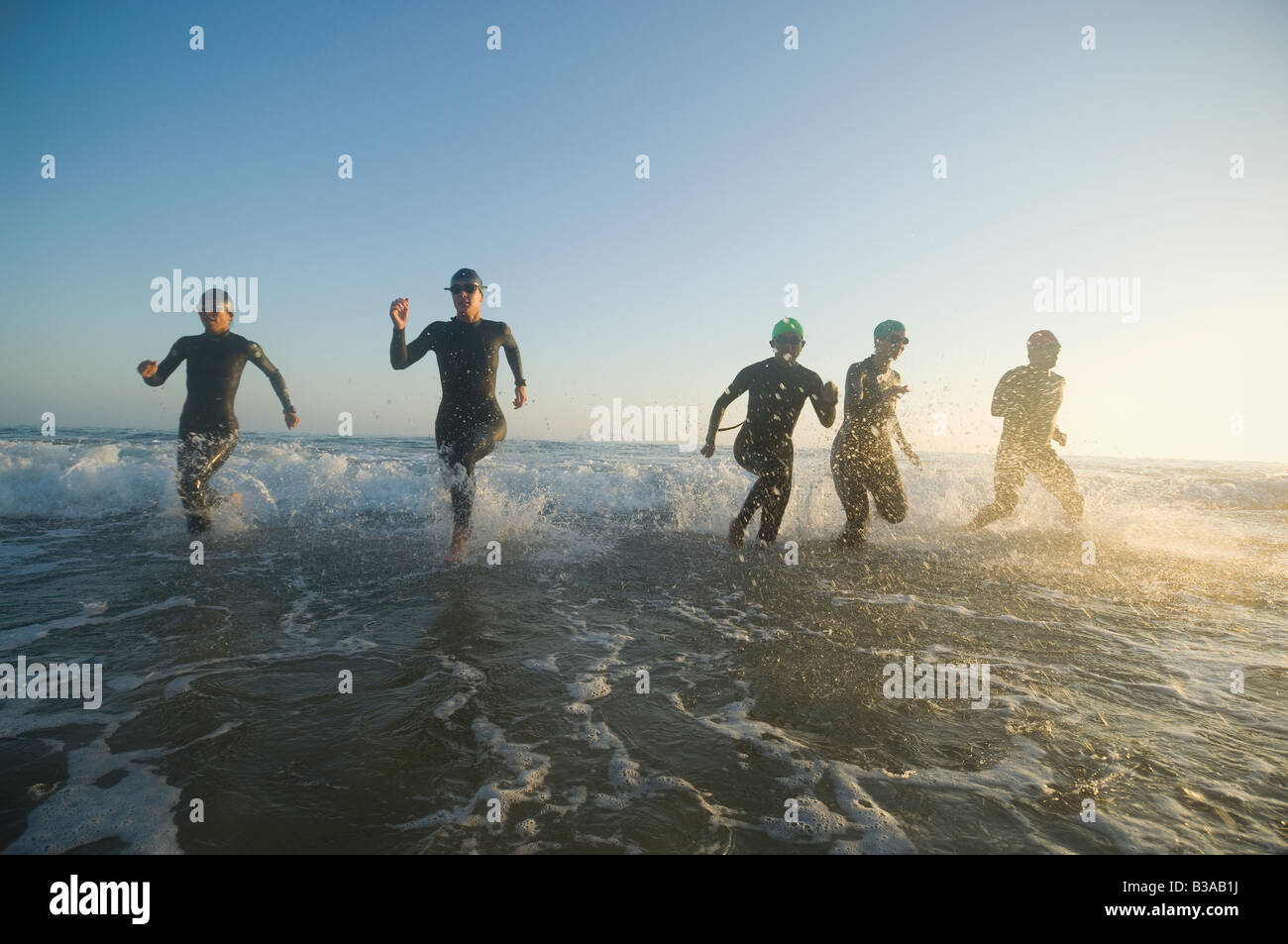 Multi-ethnic swimmers running in surf Stock Photo