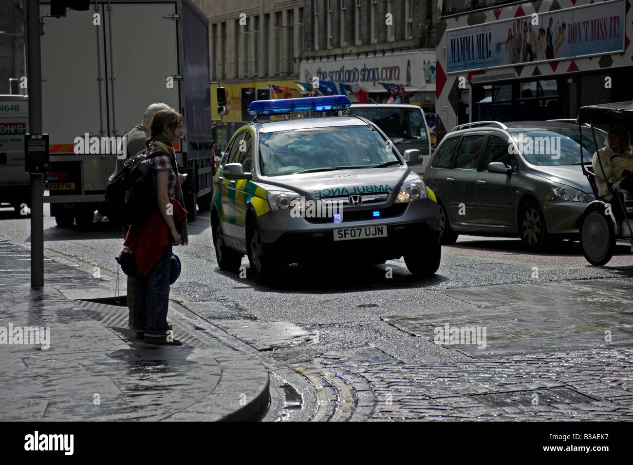 Ambulance vehicle with blue lights passing through busy junction, Edinburgh Scotland, UK, Europe Stock Photo