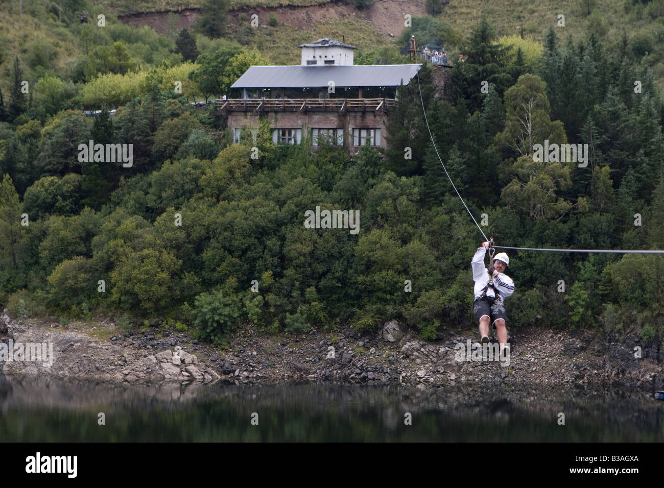 Tourist sliding down in a canopy cable in Dique Los Molinos dam Cordoba ...