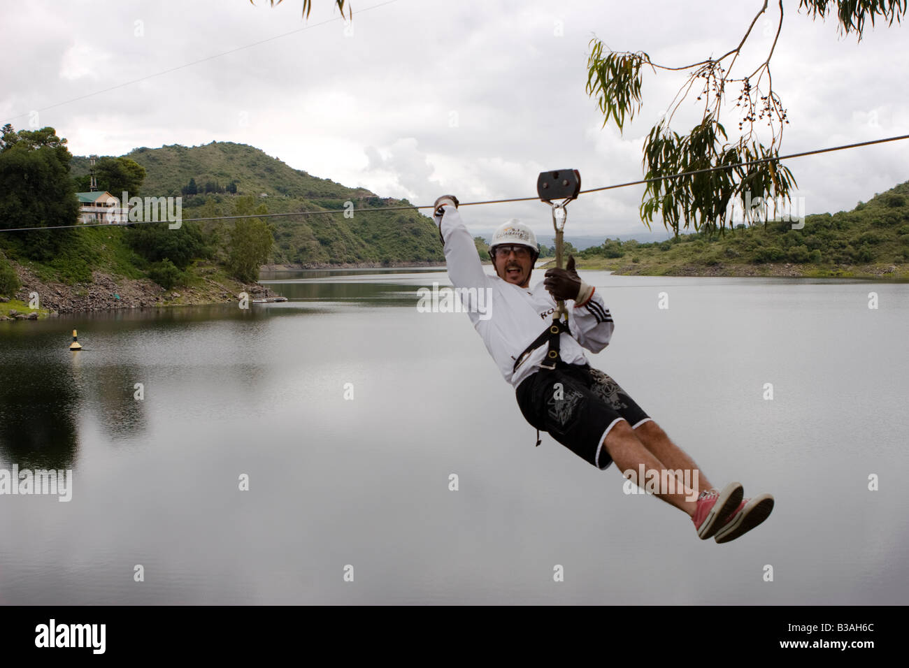 Tourist sliding down in a canopy cable in Dique Los Molinos dam Cordoba ...