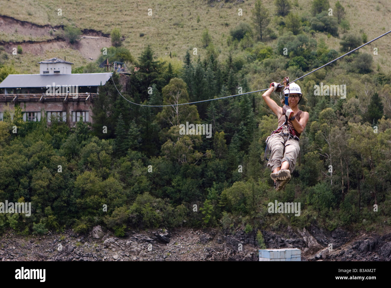 Female guide instructor sliding down in a canopy cable in Dique Los ...