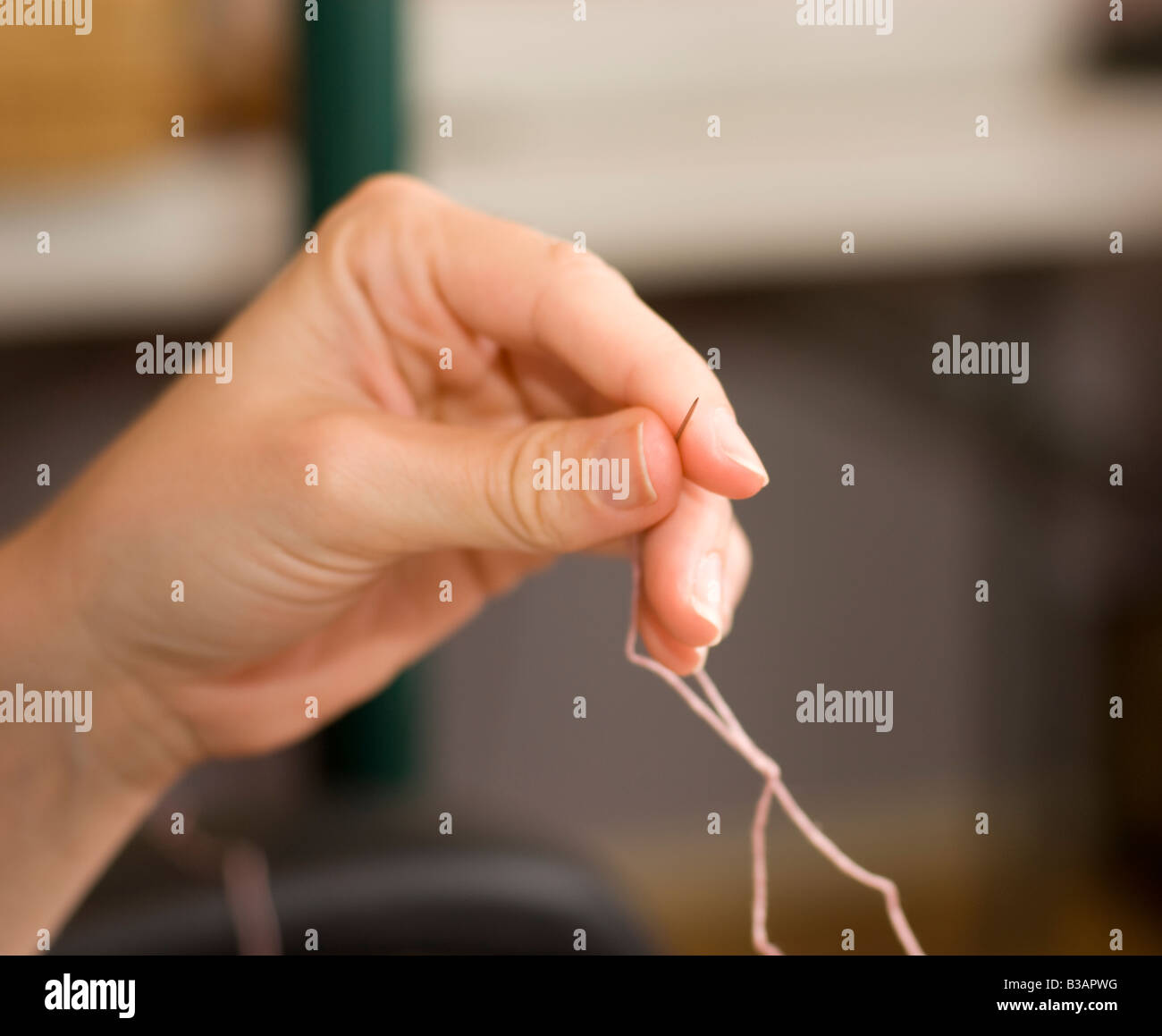 A hand holding a needle while sewing Stock Photo Alamy
