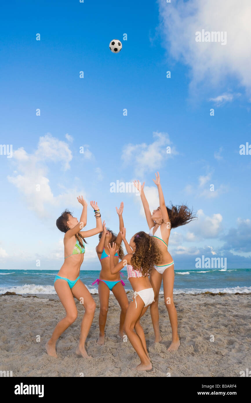 Multi-ethnic girls playing with soccer ball at beach Stock Photo