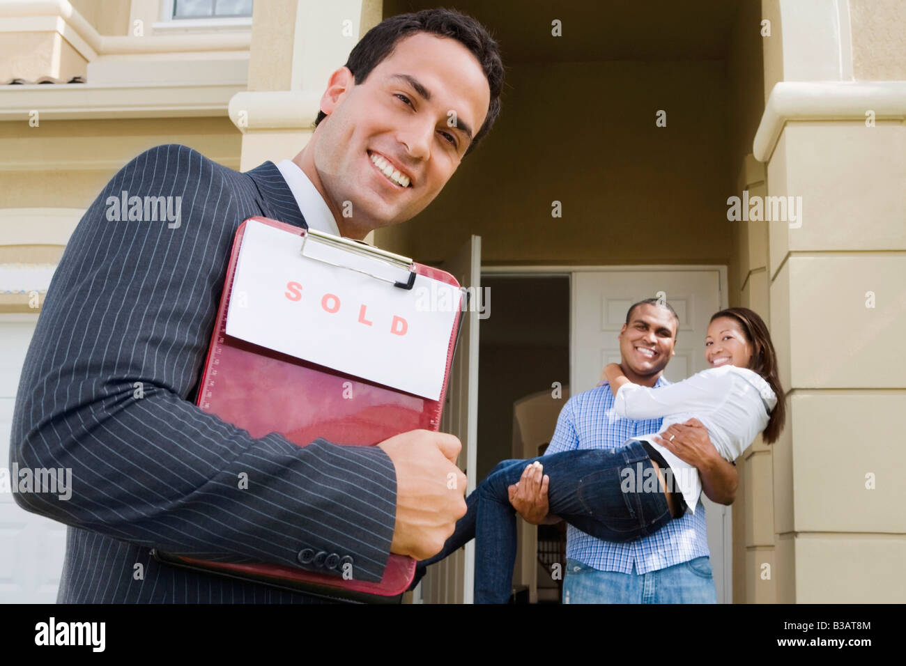 Hispanic real estate agent and African couple in front of house Stock ...